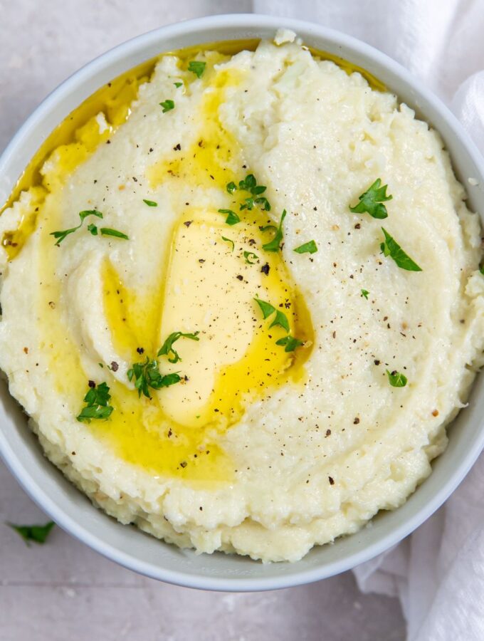 instant pot cheesy mashed cauliflower topped with butter and parsley