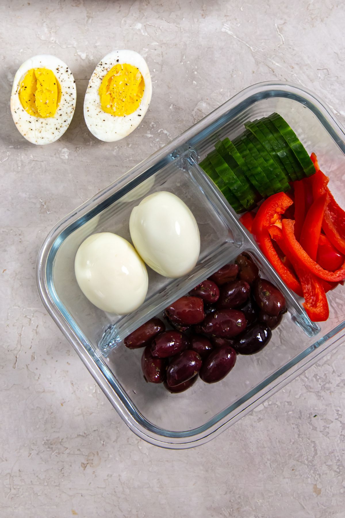 eggs, olives, cucumber, and peppers in a glass container