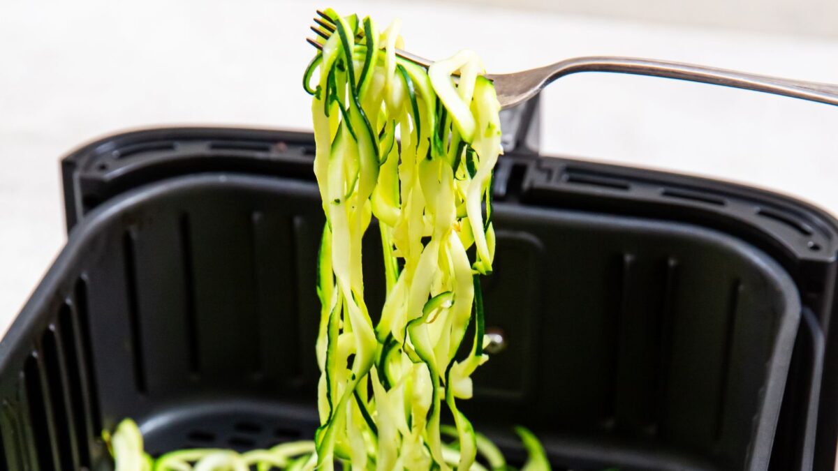 air fryer zoodles in the air fryer basket with a fork.