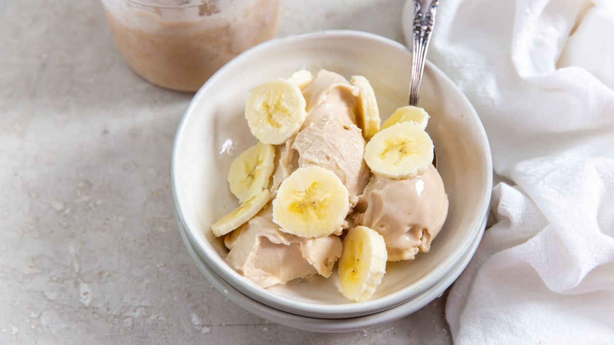 ninja creami banana protein ice cream in a white bowl topped with sliced bananas