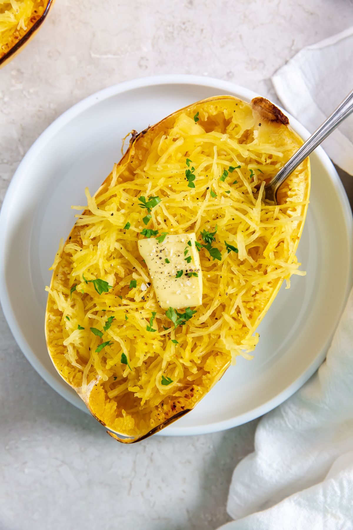 Roasted Spaghetti Squash with butter on top and a fork in it on a baking sheet