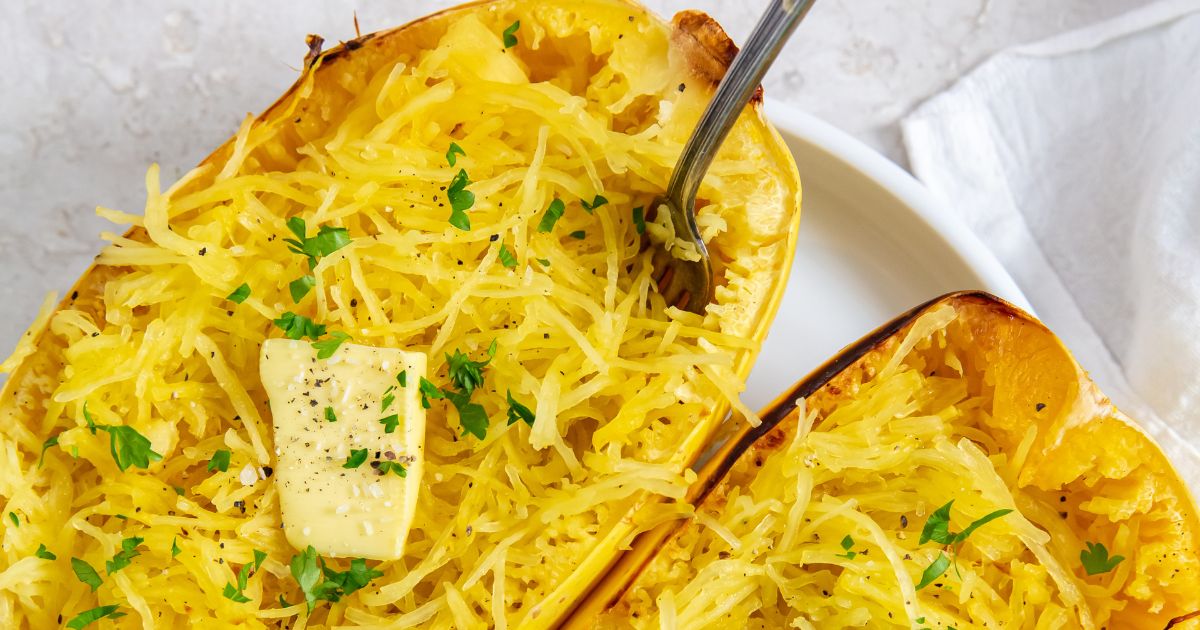 Roasted Spaghetti Squash with butter on top and a fork in it on a white plate