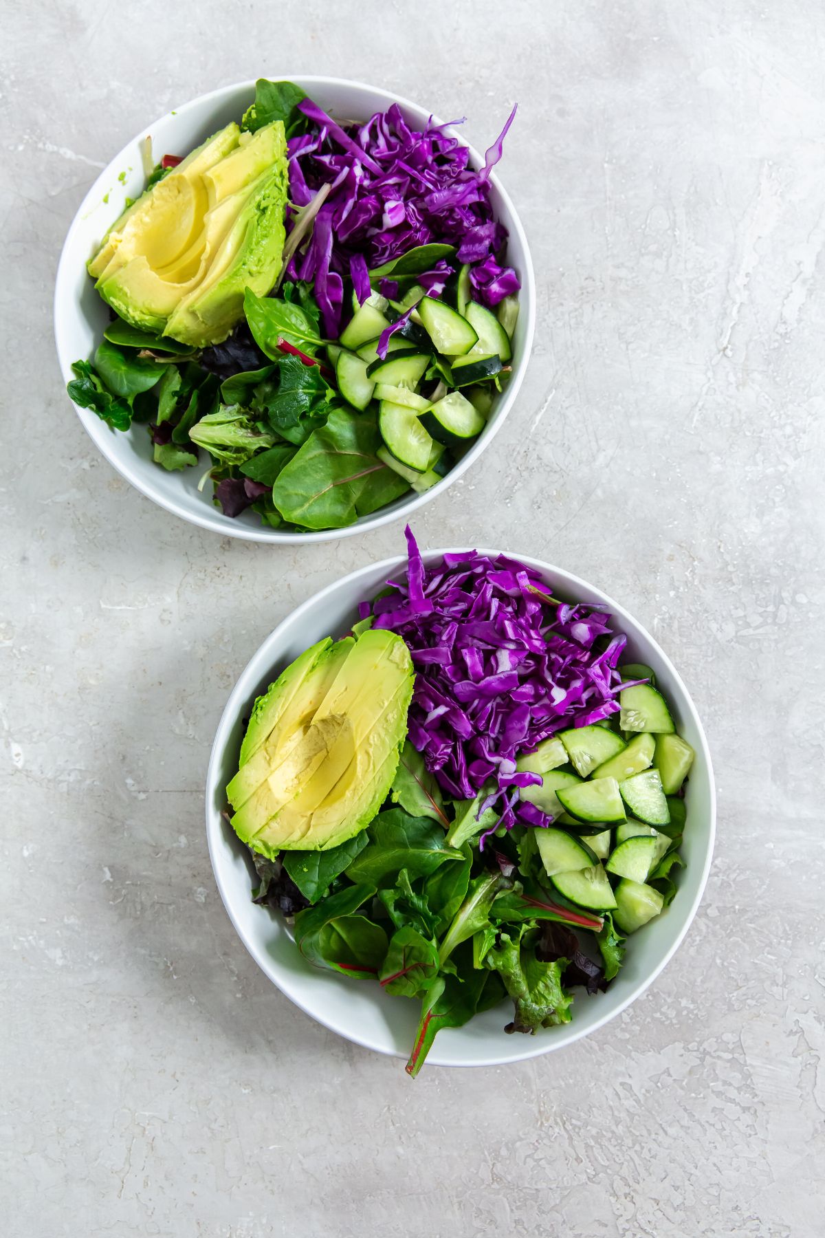 white bowl of avocado, red cabbage, and cucumber in a salad mix