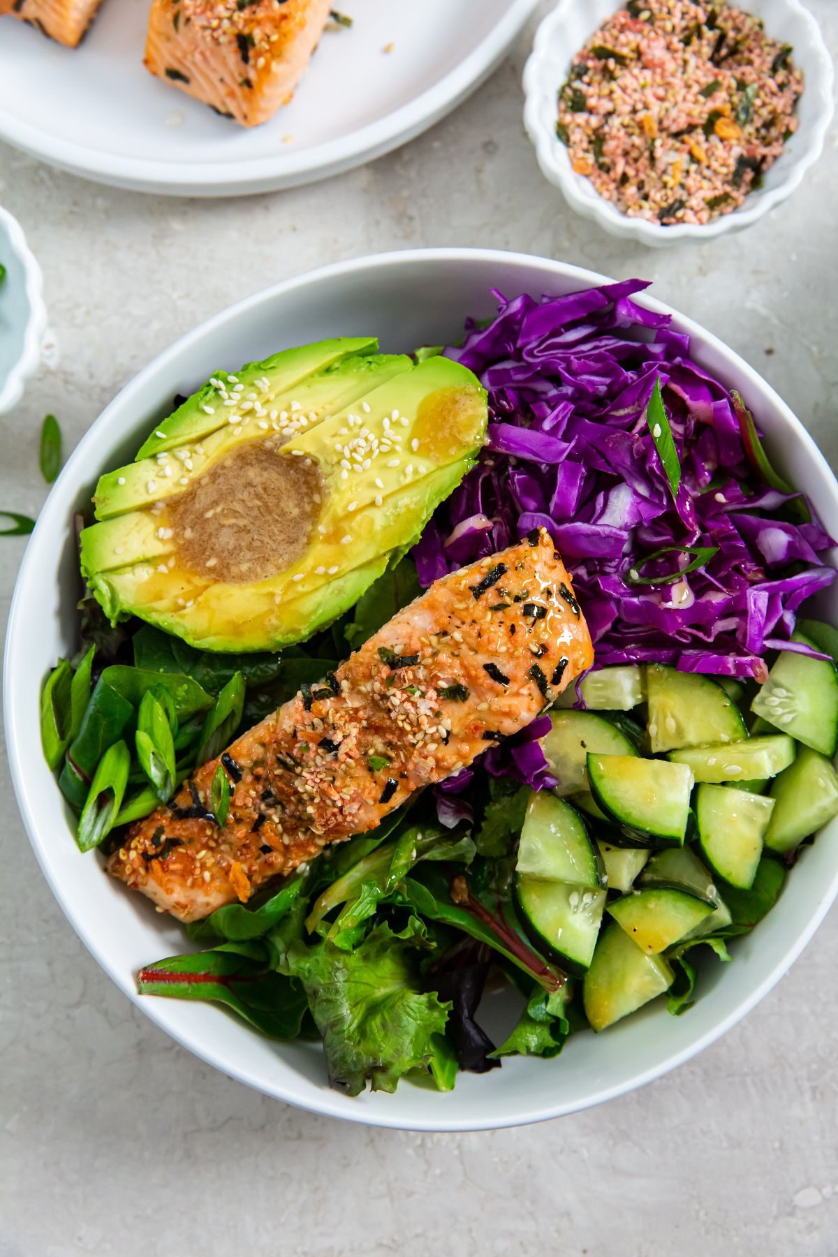 Sesame Salmon Bowl in with avocado, salmon, cabbage, cucumber with a sesame dressing.