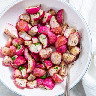 Air Fyer radishes in a white bowl with a spoon in it and a white napkin on the side