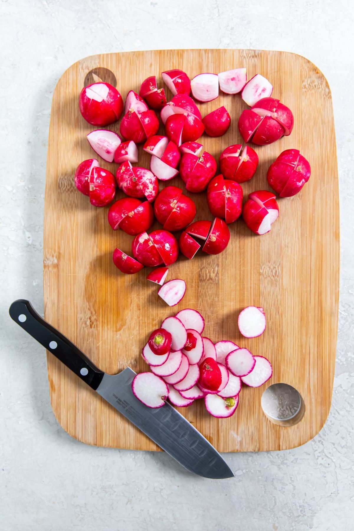 Radishes on a cutting board with a knife cut in half
