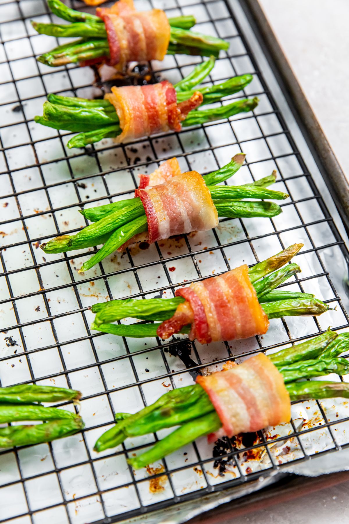 bacon wrapped green beans on a baking sheet