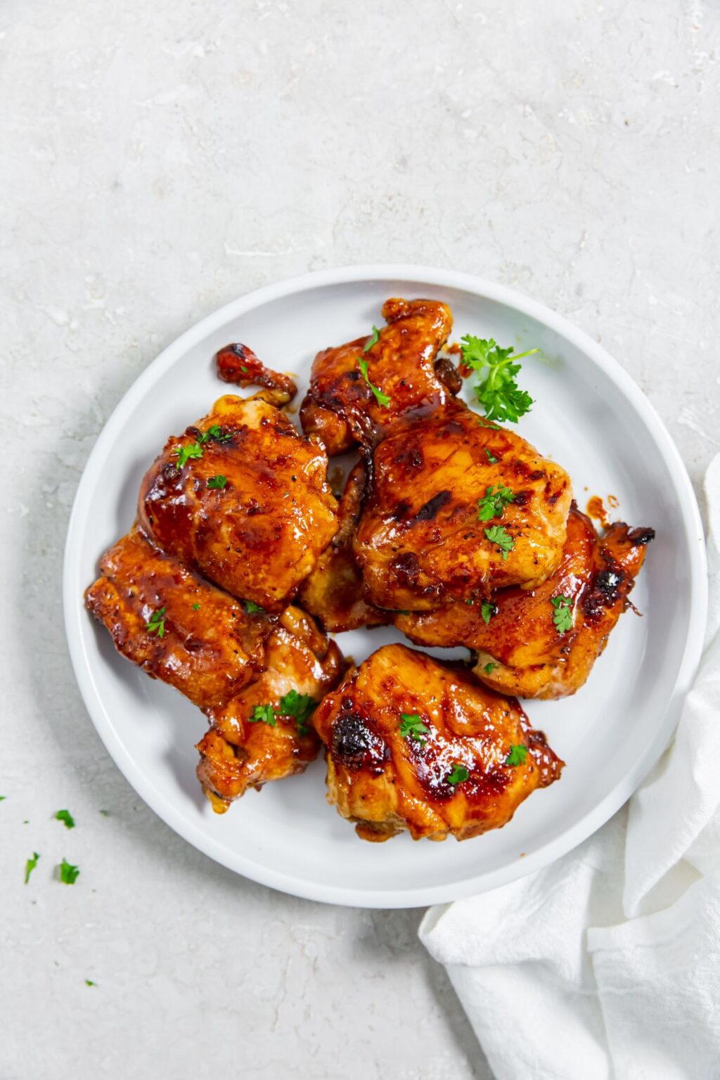 Honey Lemon Pepper Thighs with parsley on a white plate.