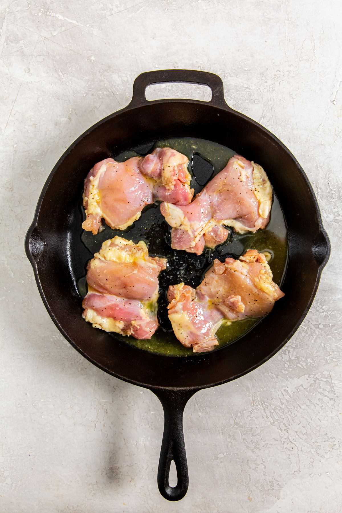 cast iron skillet with raw chicken thighs on it