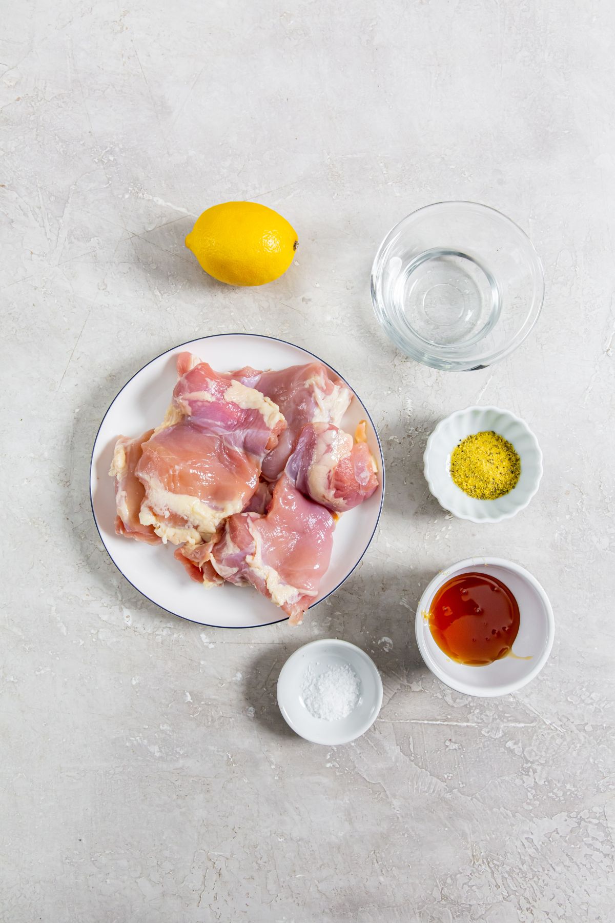 ingredients of chicken thighs, lemon, water, honey, lemon pepper seasoning, and salt