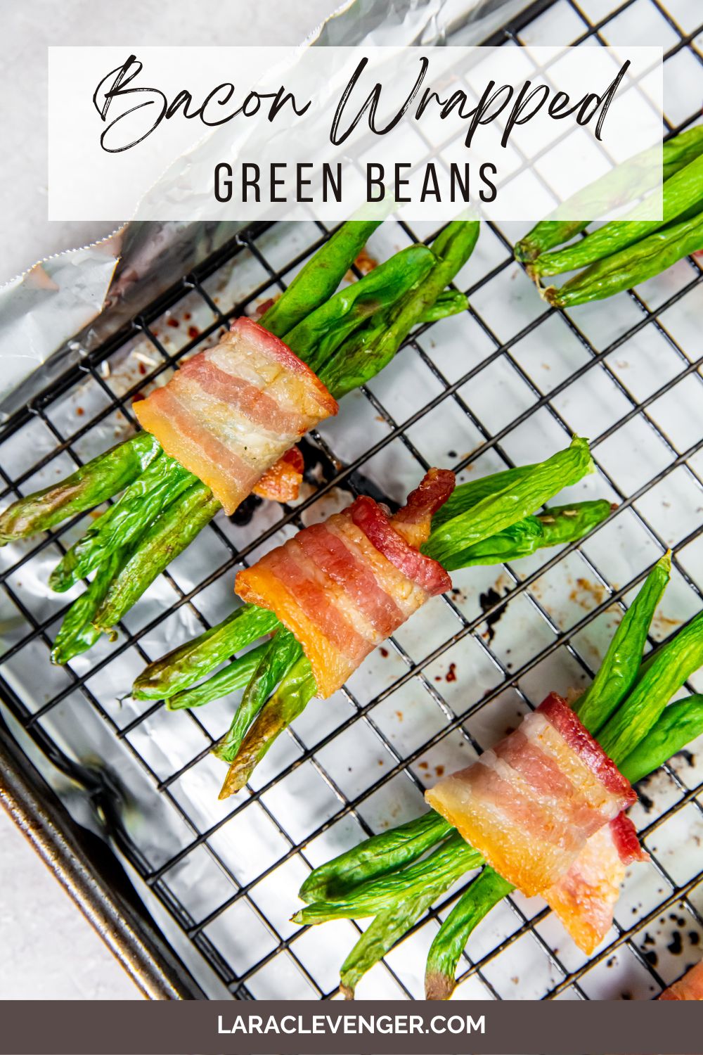 pin of bacon wrapped green beans on a baking sheet