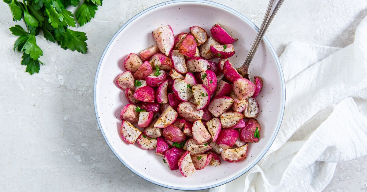 Air Fyer radishes in a white bowl with a spoon in it and a white napkin on the side