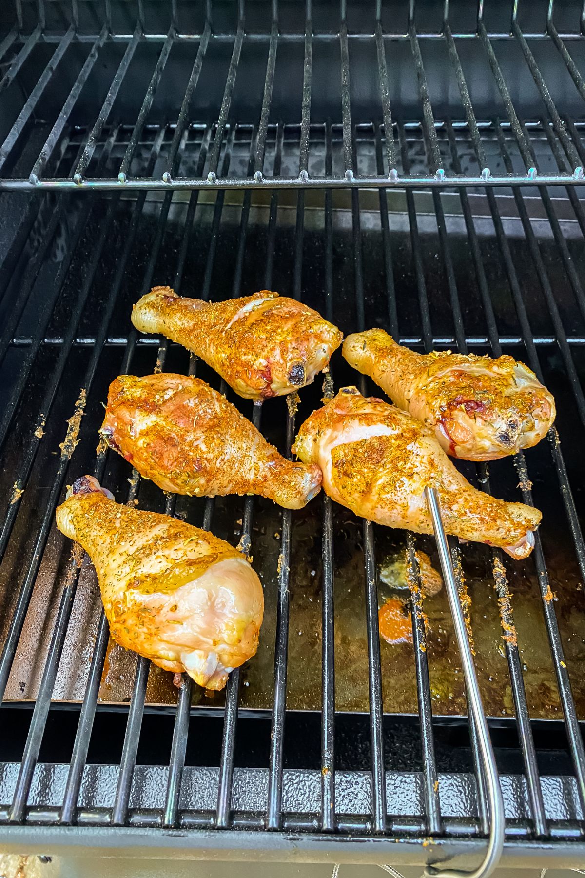 chicken drumsticks in the smoker with a thermometer in it