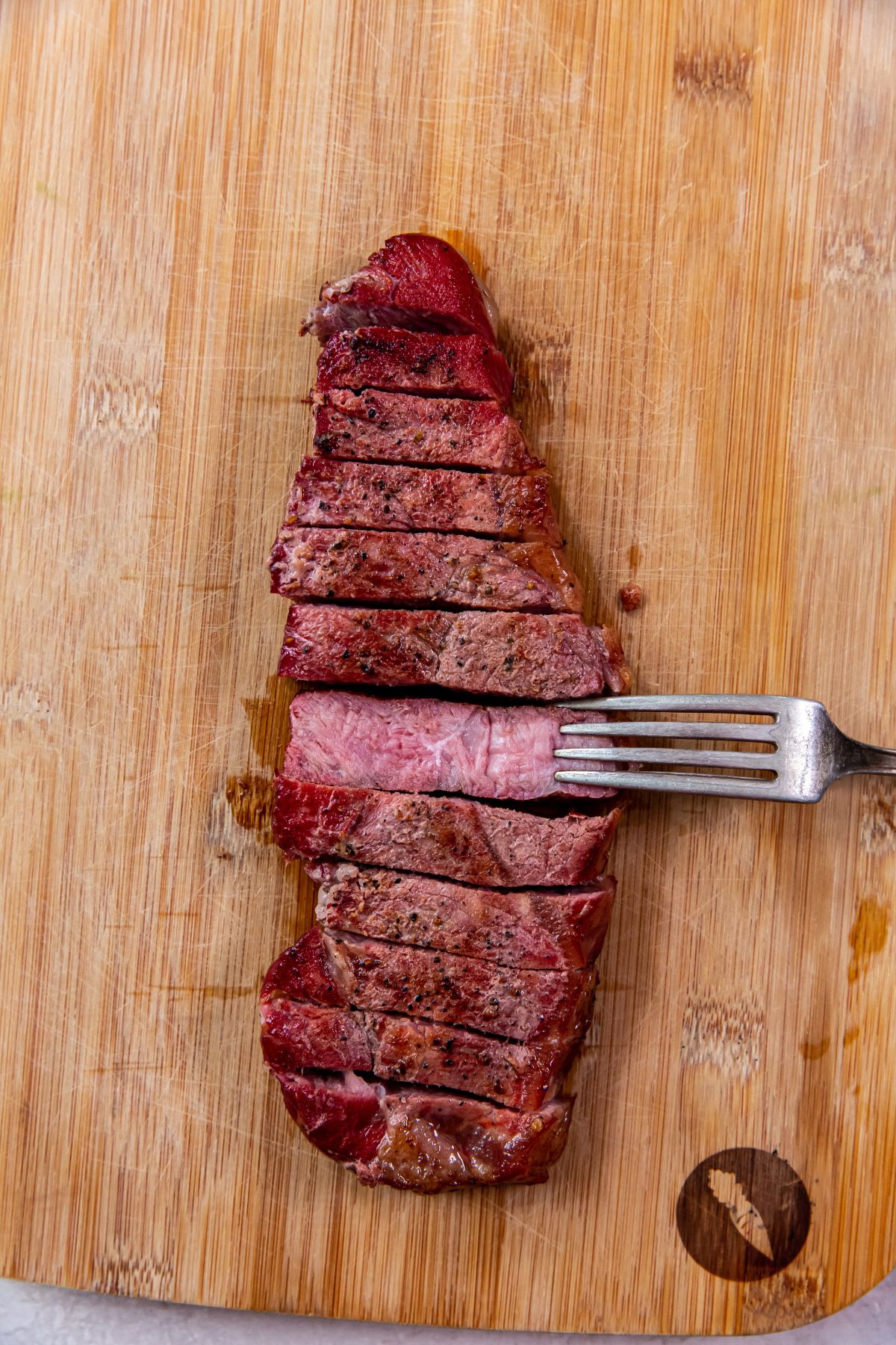 Smoked New York Strip Steaks on a cutting board with a fork