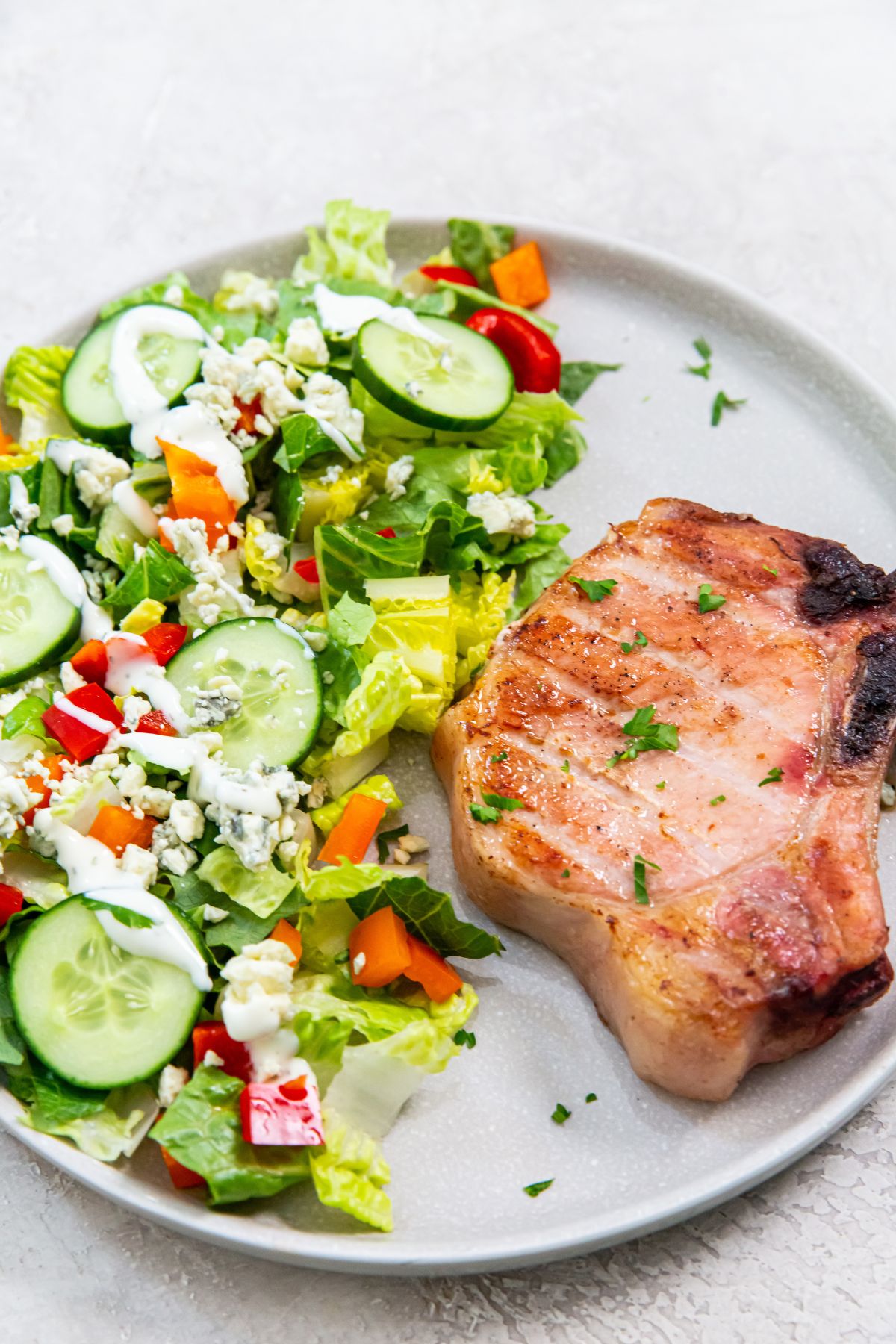 Smoked bone in pork chops on a plate with a salad