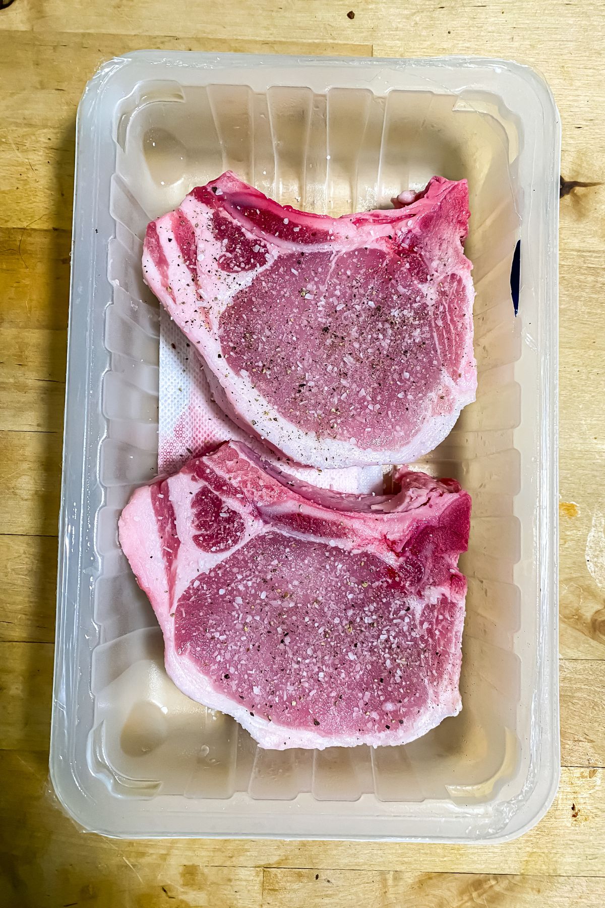 raw pork chops with seasoning on top