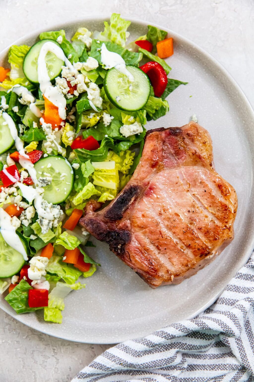 Traeger Smoked Pork Chop with a salad on a light gray plate