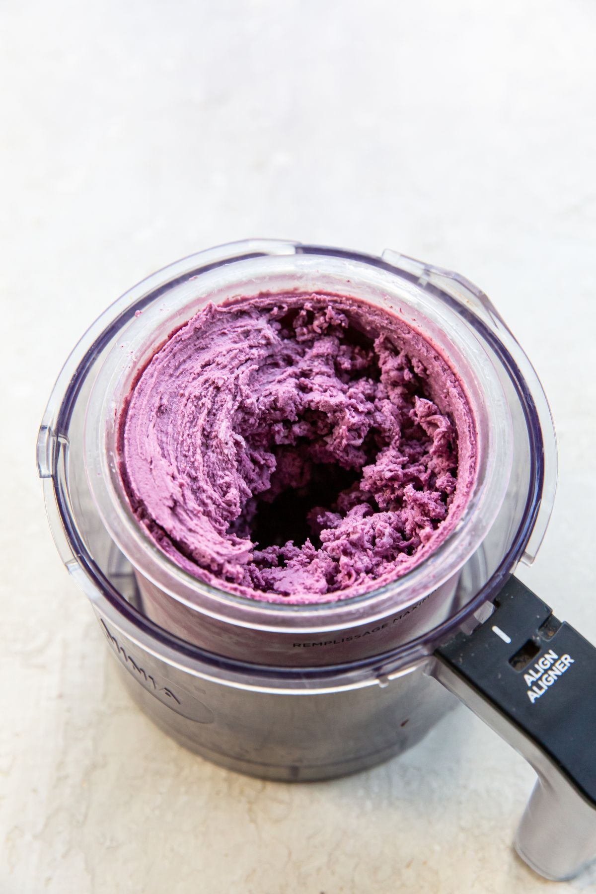 A blender filled with blueberry puree for making blueberry cheesecake ice cream.