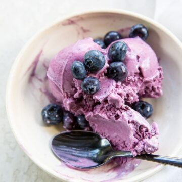 Blueberry cheesecake ice cream served in a bowl with a spoon.
