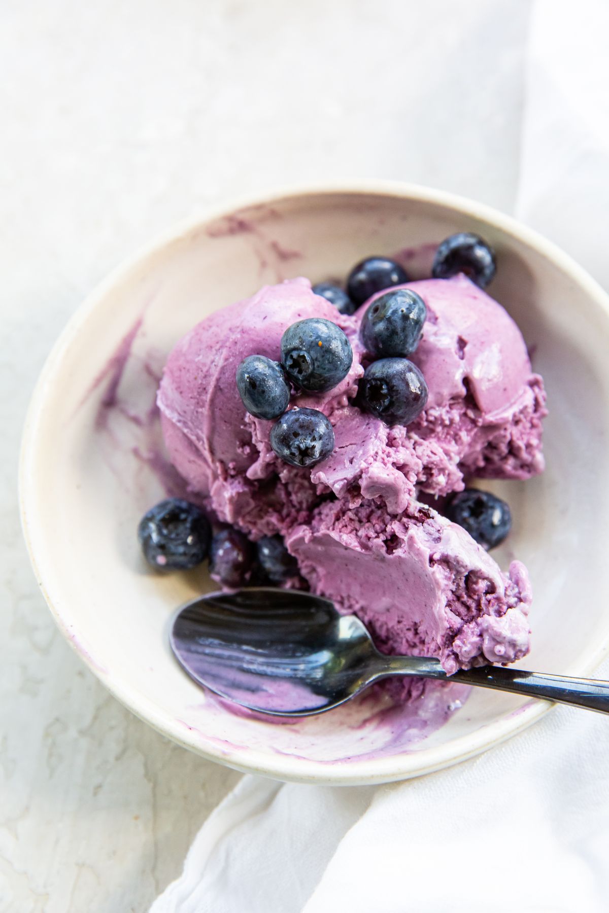 Blueberry cheesecake ice cream served in a bowl with a spoon.