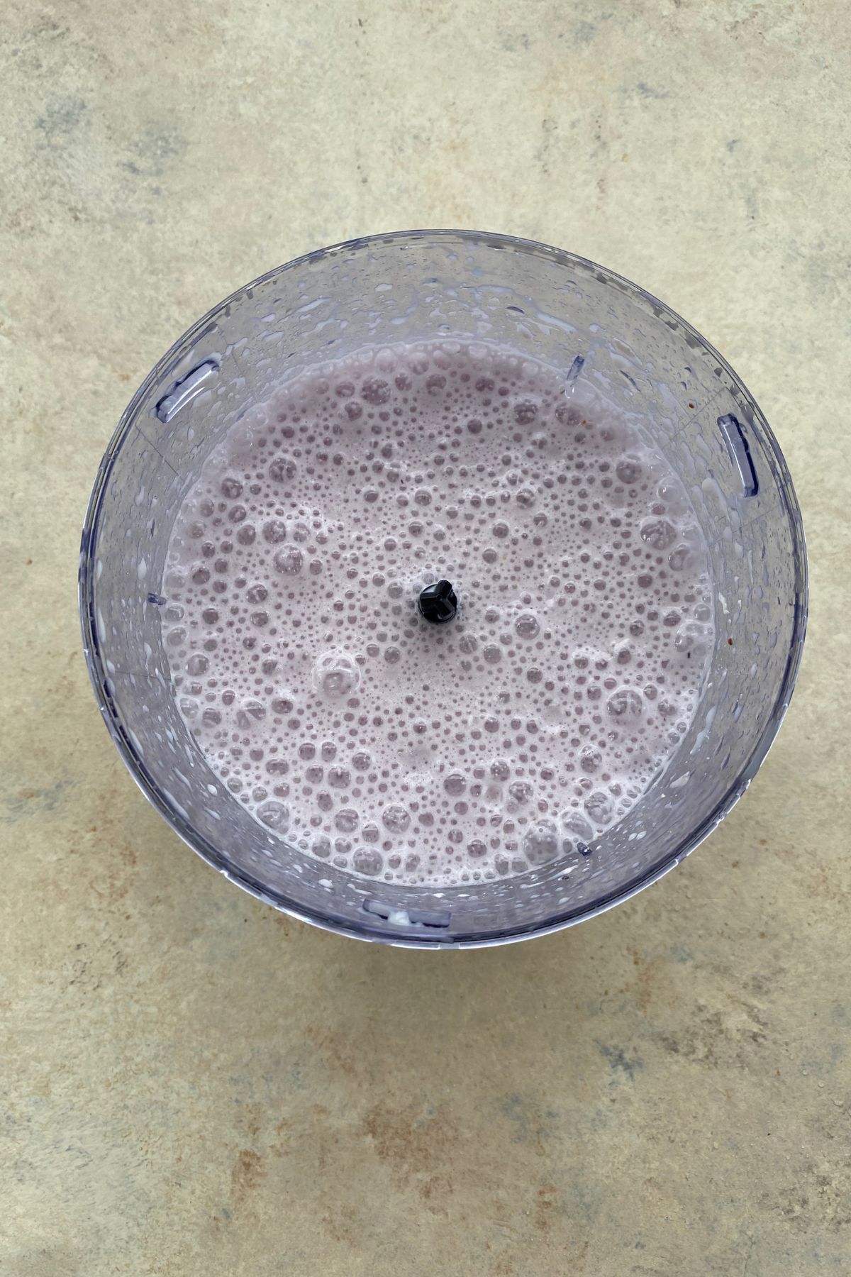 A bowl of liquid with a blackberry and blueberry.