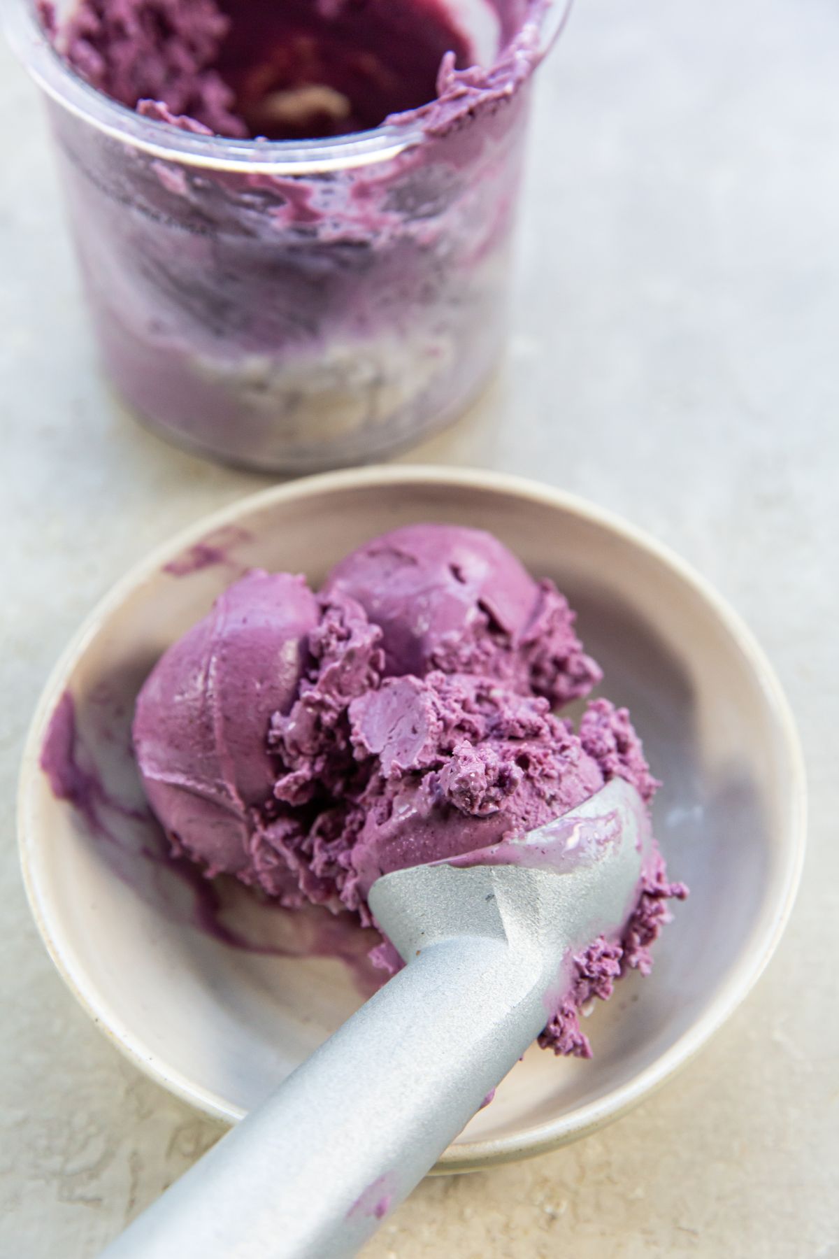 Purple Blueberry Cheesecake ice cream in a bowl with a spoon.