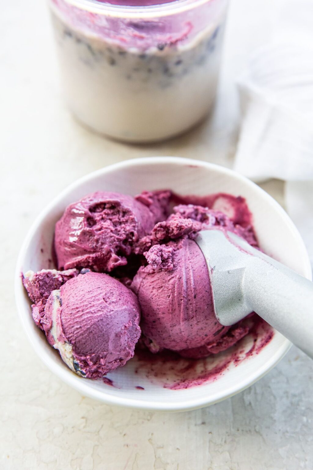 Blueberry Ice Cream in white bowl with an ice cream scoop