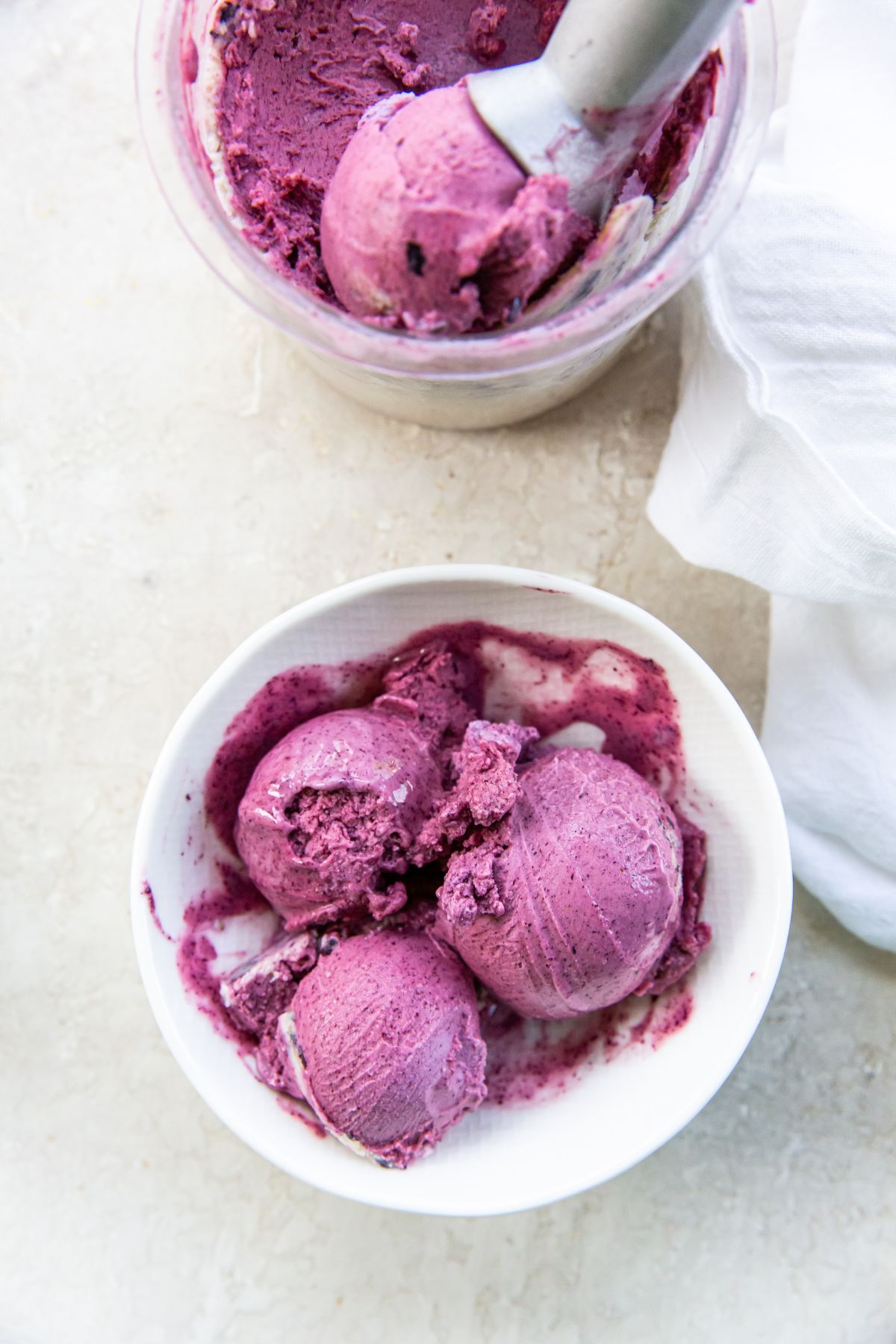 A blueberry ice cream bowl with a scoop in it.