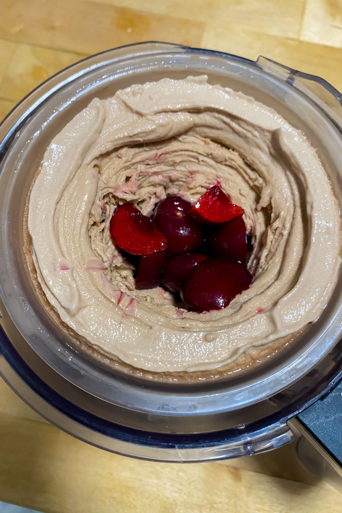 A bowl of hummus with cherries and chocolate.