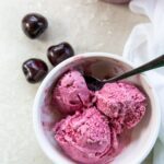 Cherry ice cream in a bowl with cherries.
