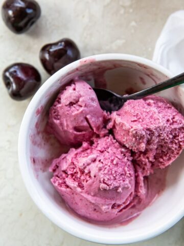 Cherry ice cream in a bowl with a spoon.