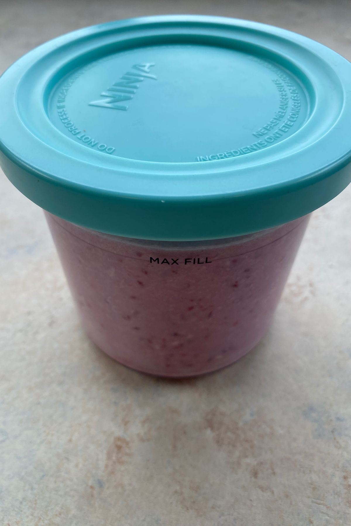 A pink container with a lid sitting on a table.