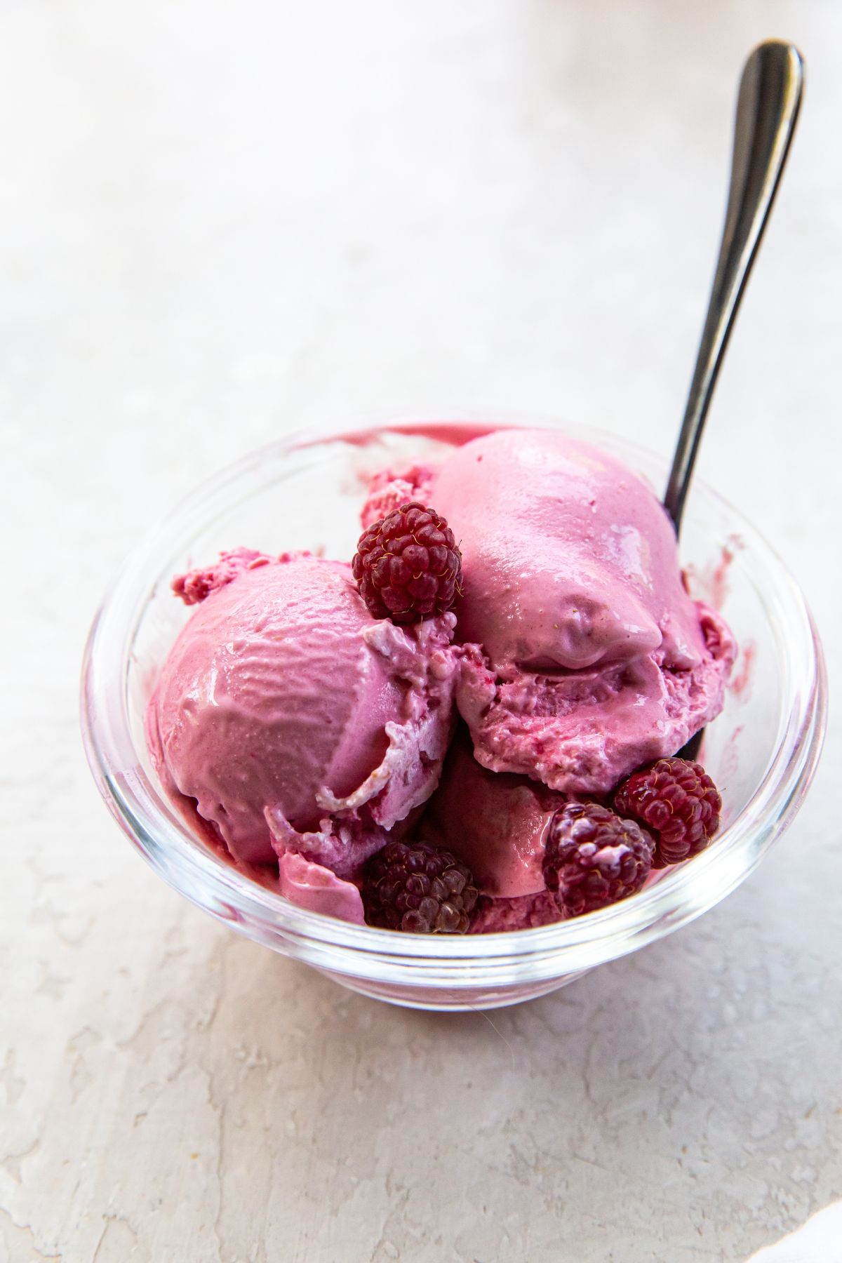 A bowl of raspberry ice cream with a spoon.