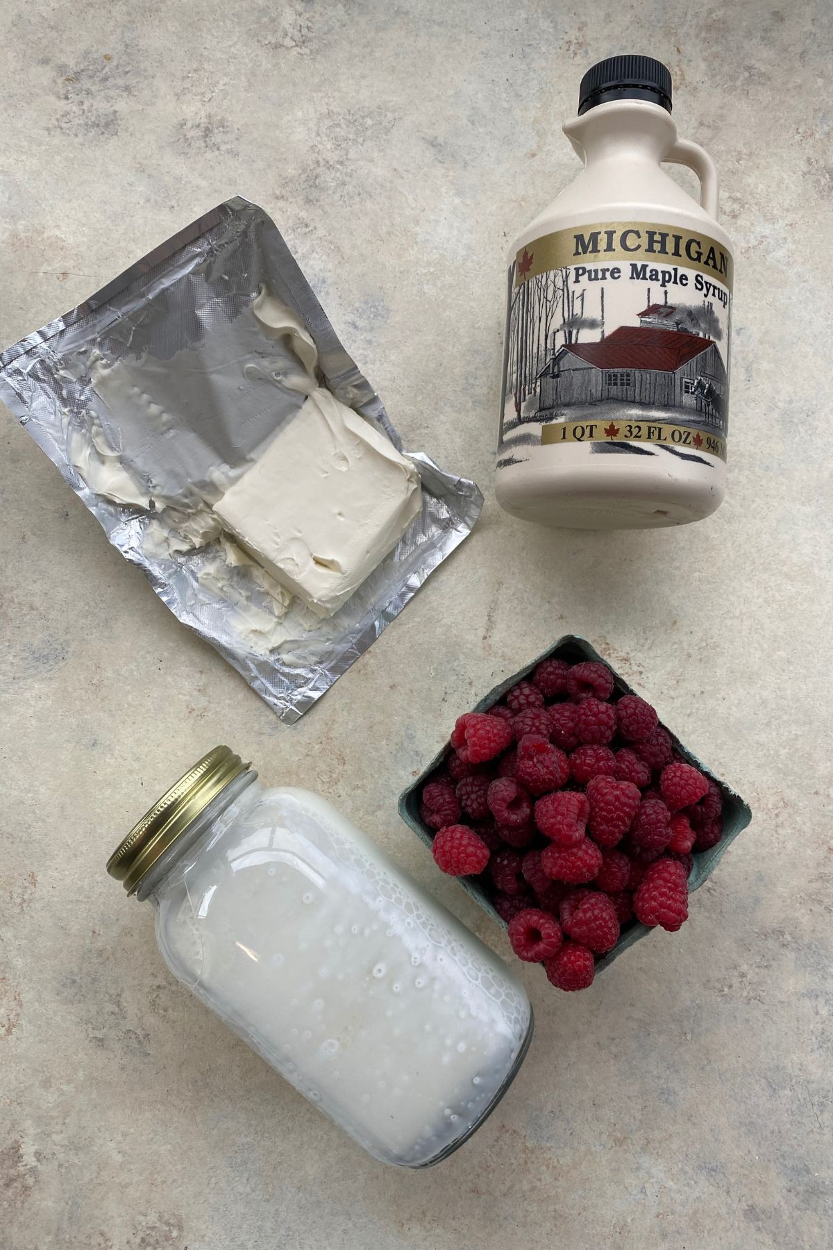 A jar of milk, raspberries and raspberries on a table.