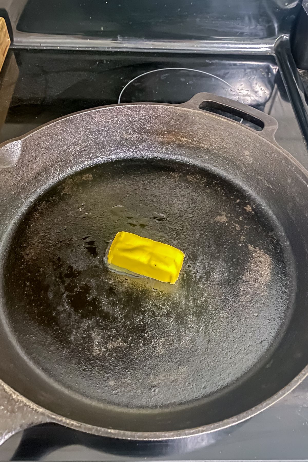 A frying pan with a yellow piece of butter in it.