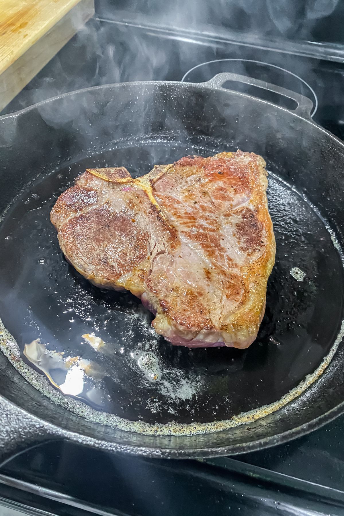 A steak is being cooked in a frying pan.