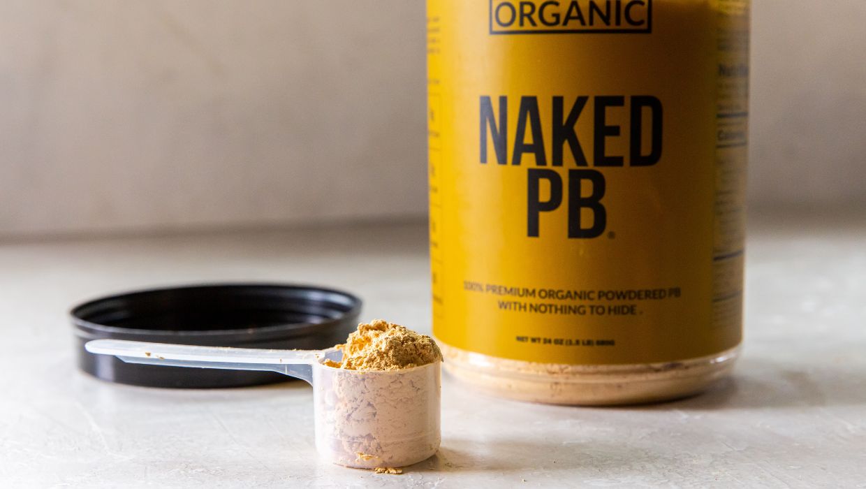 A bottle of naked pb with a spoon next to it.
