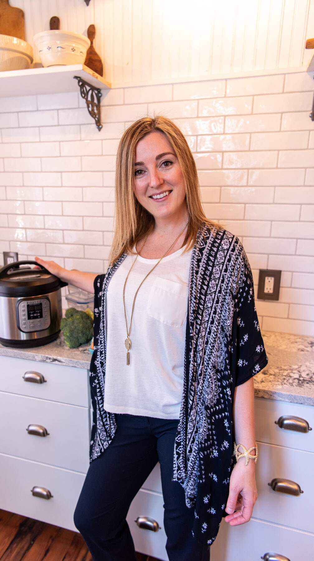 A woman standing in front of a kitchen with an instant pot, keto coach.