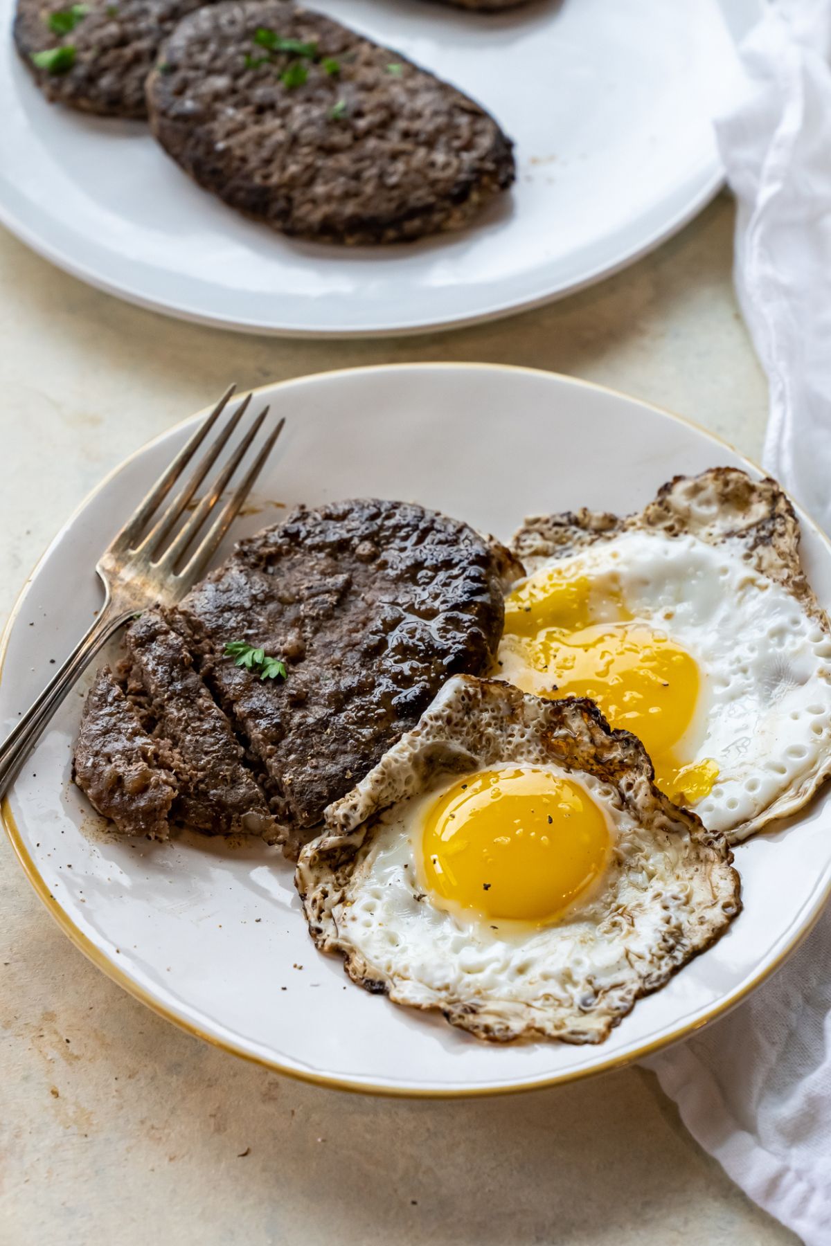 A plate of steak and eggs with a fork.