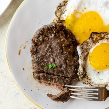 A plate with a steak and eggs on it.