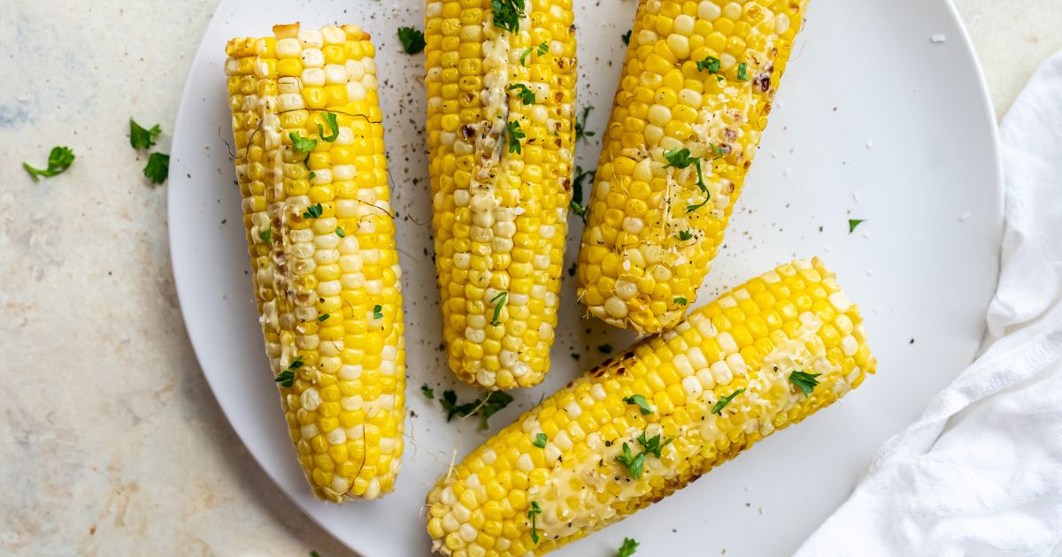 Grilled corn on the cob on a white plate.