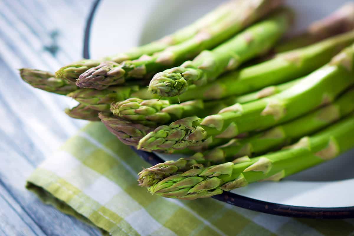 A bunch of fresh asparagus spears on a plate.