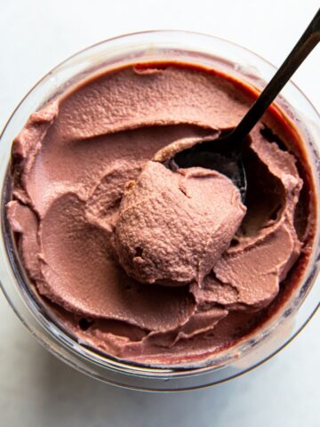 chocolate cherry ice cream in a clear pint with a spoon.