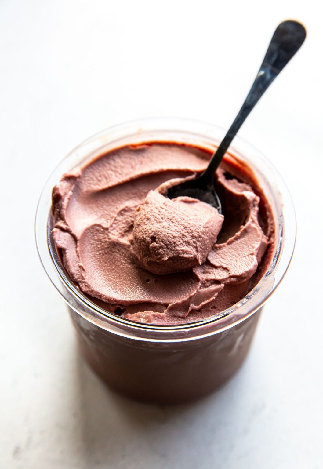 chocolate cherry ice cream in a clear pint with a spoon.