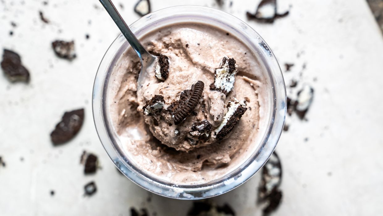 cookies and cream ice cream in a clear pint with Oreos and a spoon.