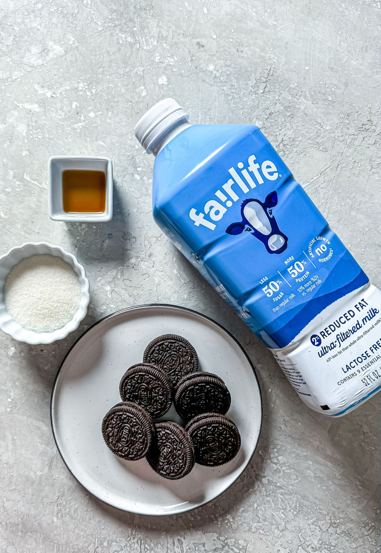 milk, Oreos, vanilla, and sweetener on a light surface.