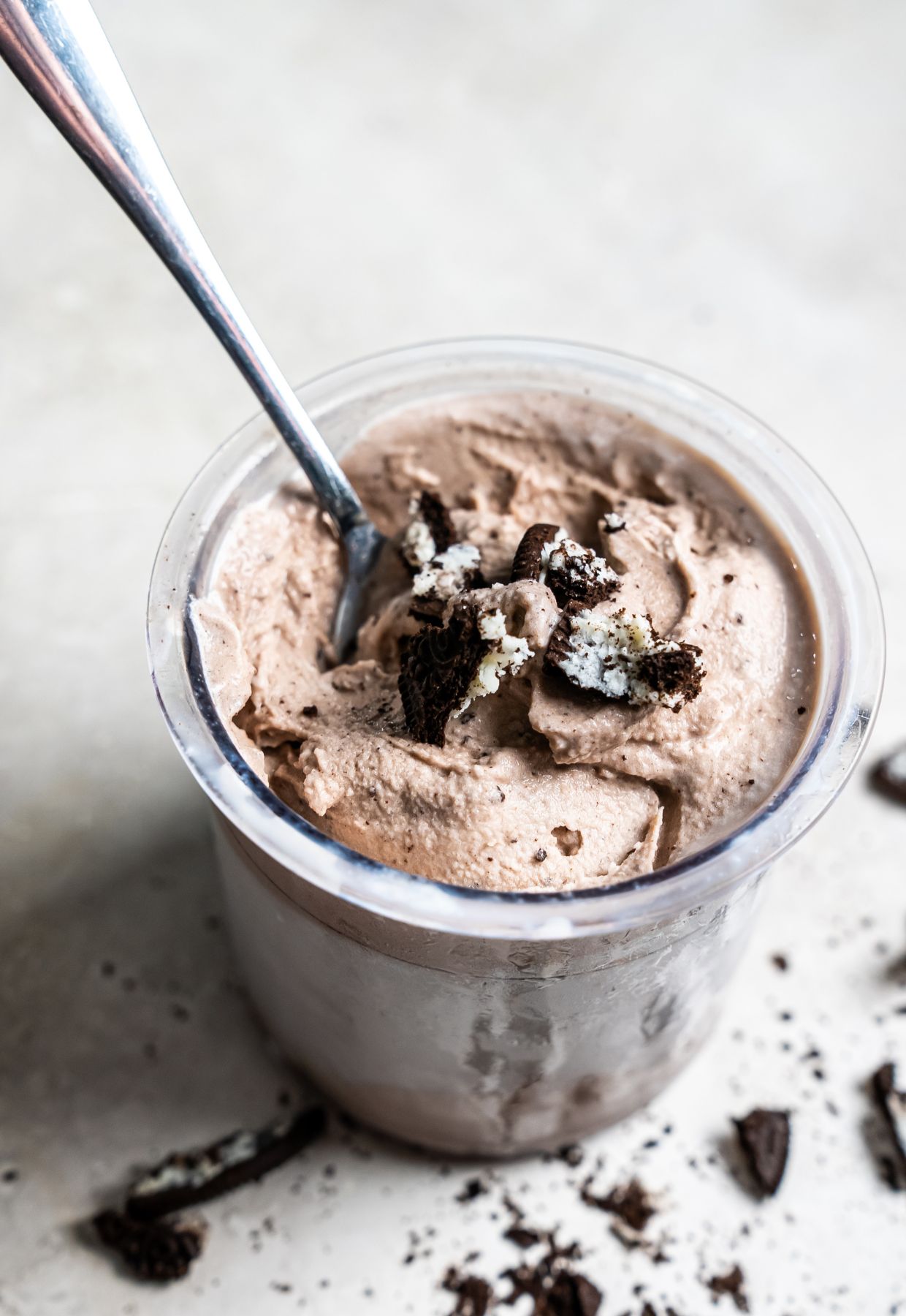 cookies and cream ice cream in a clear pint with Oreos and a spoon.