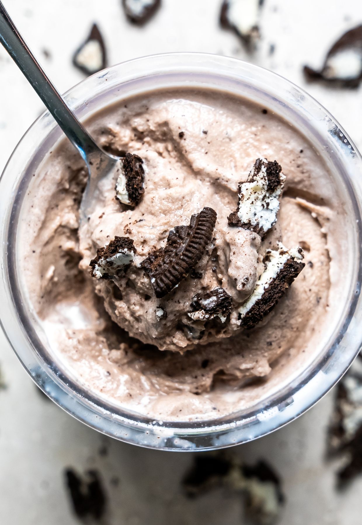 cookies and cream ice cream in a clear pint with Oreos and a spoon.