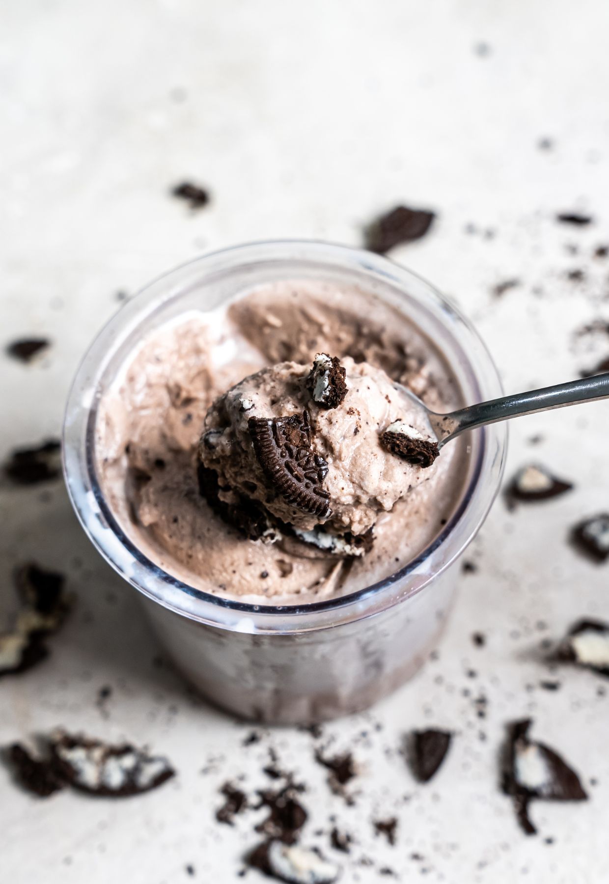 cookies and cream ice cream in a clear pint with Oreos and a spoon.