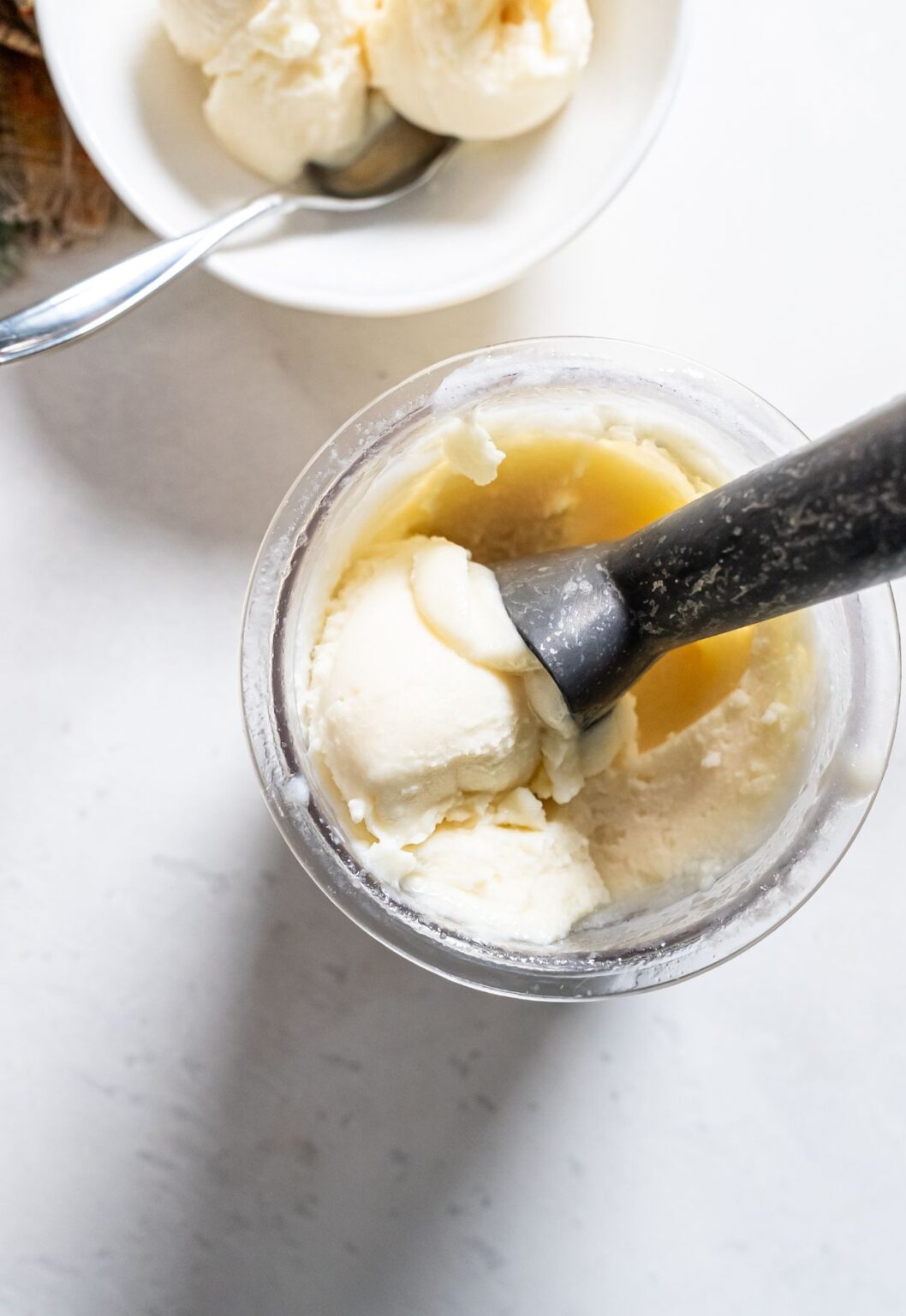 dole whip in a ninja creami pint with a ice cream scoop.